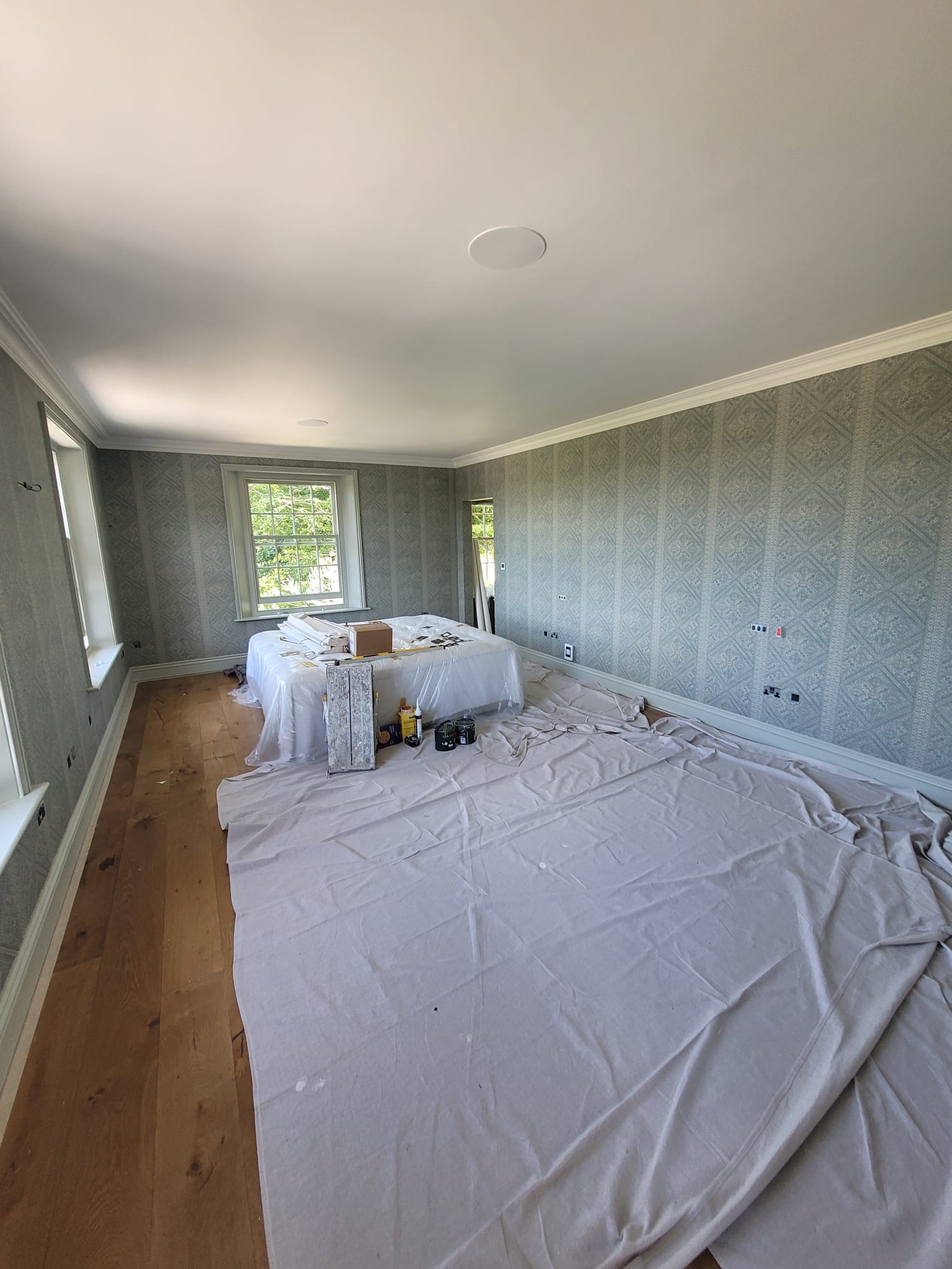 Room with elegant patterned wallpaper, white ceiling, and period detailing